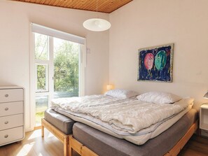 A bedroom with a bed, a dresser, a painting, and a window.