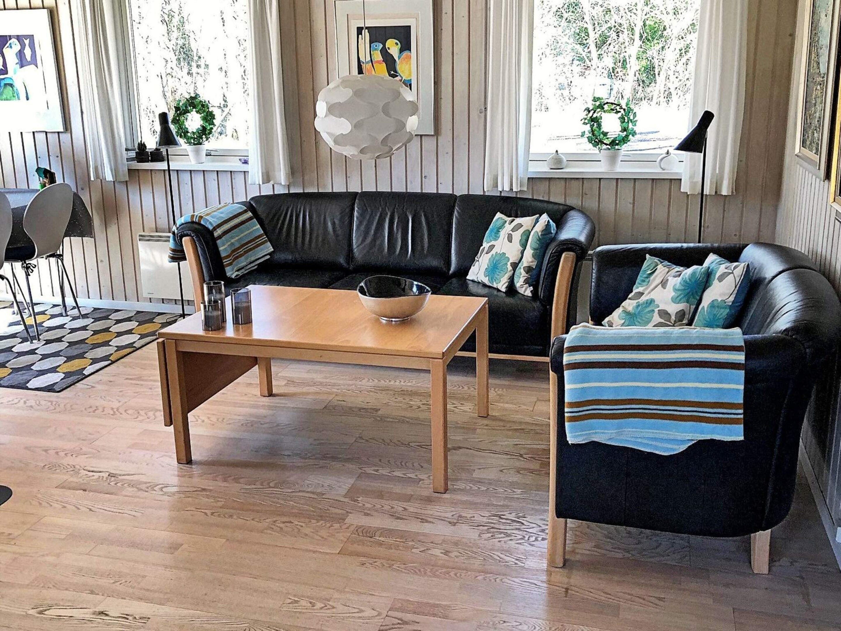 A living room with a black leather sofa, a wooden coffee table, and a striped throw blanket.