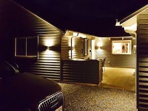 A residential property at night with a driveway, a car, and a well-lit entrance.