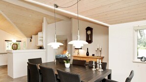 A dining area with a large wooden table and wicker chairs, a chandelier, and a clock on the wall. - 6 Person Holiday Home in Ansager-by Traum (Ansager)