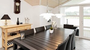 A dining area with a long wooden table, black chairs, a wooden cabinet, a clock, and pendant lights. - 6 Person Holiday Home in Ansager-by Traum (Ansager)