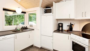A modern kitchen with white cabinets, a built-in microwave, a coffee maker, and a stove. - 6 Person Holiday Home in Ansager-by Traum (Ansager)