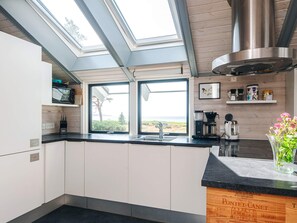 Une cuisine moderne dotée de fenêtres de toit, d’une hotte en acier inoxydable et offrant une vue sur l’extérieur.