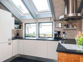 A modern kitchen with skylights, a stainless steel range hood, and a view of the outdoors.