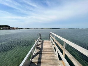 A wooden pier extending into a calm body of water with a clear sky above.