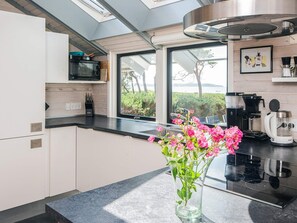 A modern kitchen with a skylight, a view of greenery, and a coffee maker.