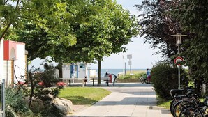 A pathway leading to a beach with a lifeguard tower, benches, and bicycles parked along the side. - Holiday Home in Großenbrode (Grossenbrode)