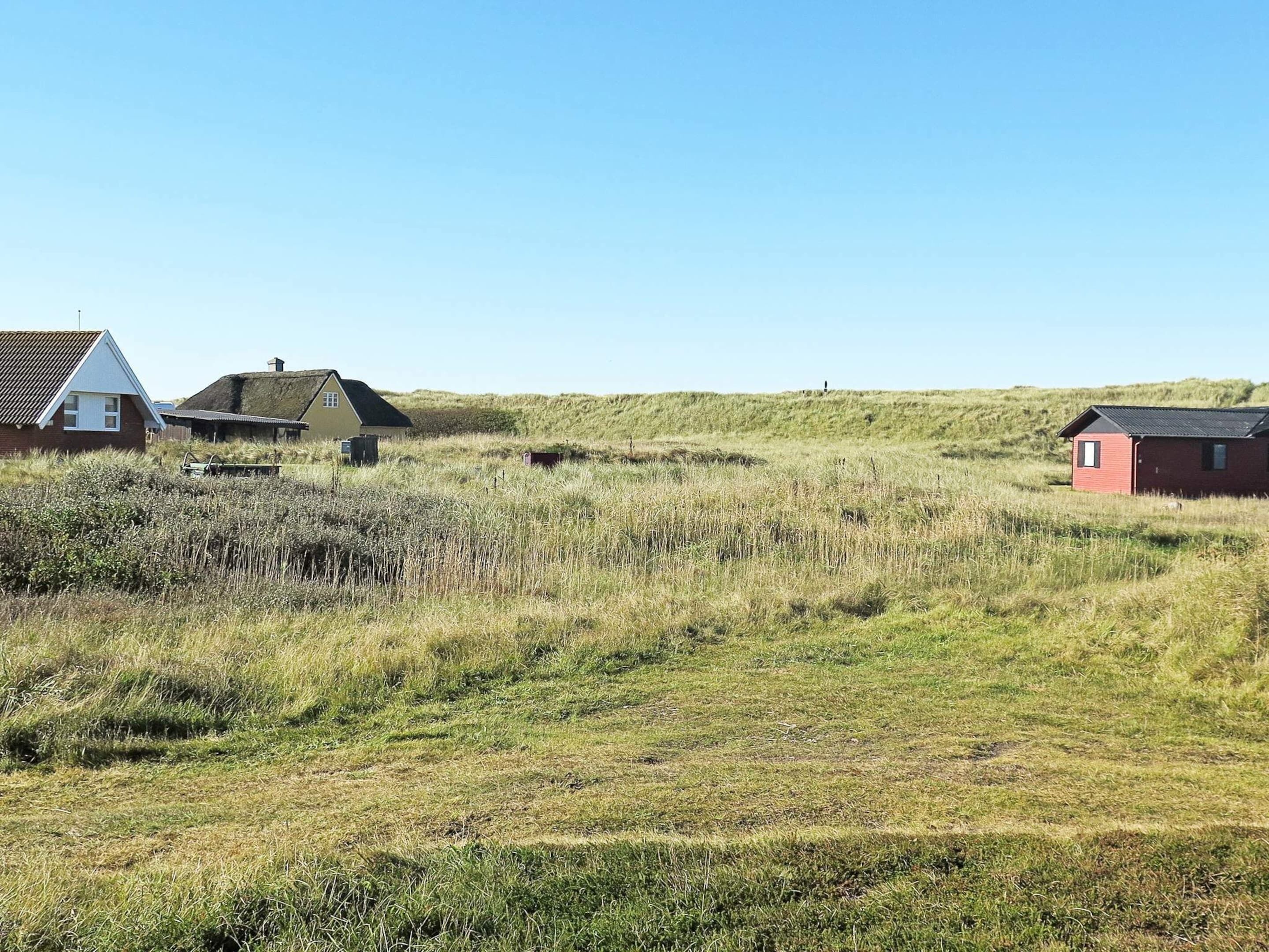 A rural landscape with houses and grass fields.
