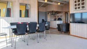 A modern interior with a dining area, kitchen, and a TV mounted on the wall. - 4 Star Holiday Home in Lemvig (Lemvig)