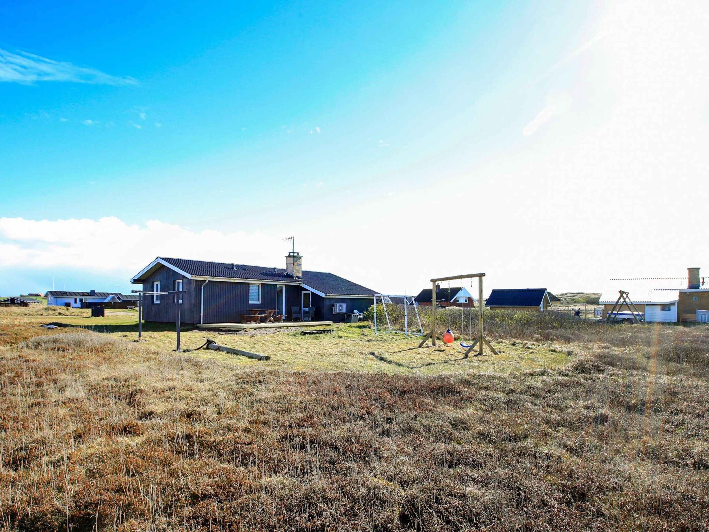Ett bostadsområde med hus, en gunga och en gräsyta.