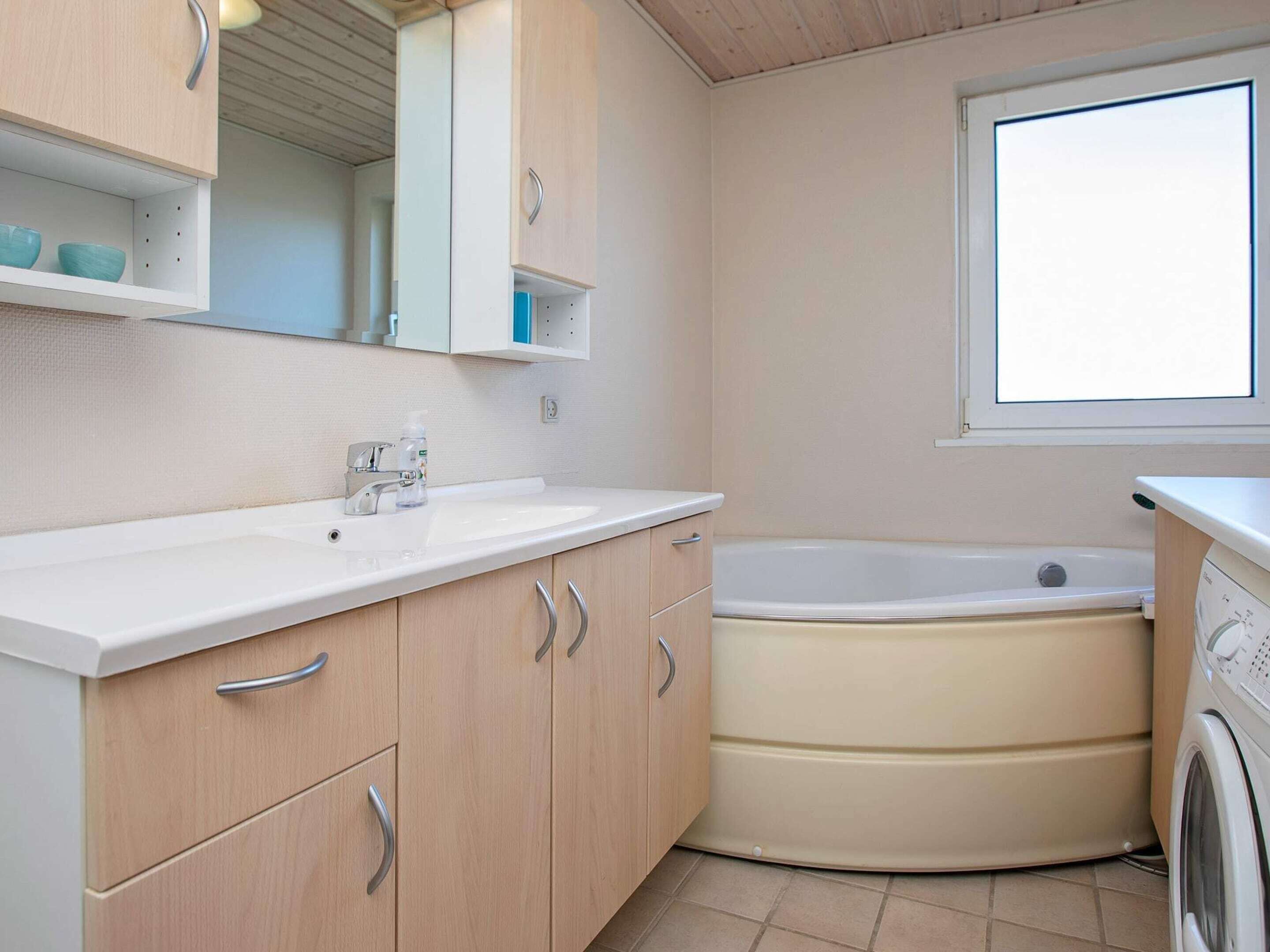 Une petite salle de bain comprenant un lavabo, un miroir, un meuble et une baignoire.