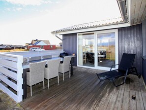 A deck with outdoor furniture, a grill, and a view of the surrounding area.