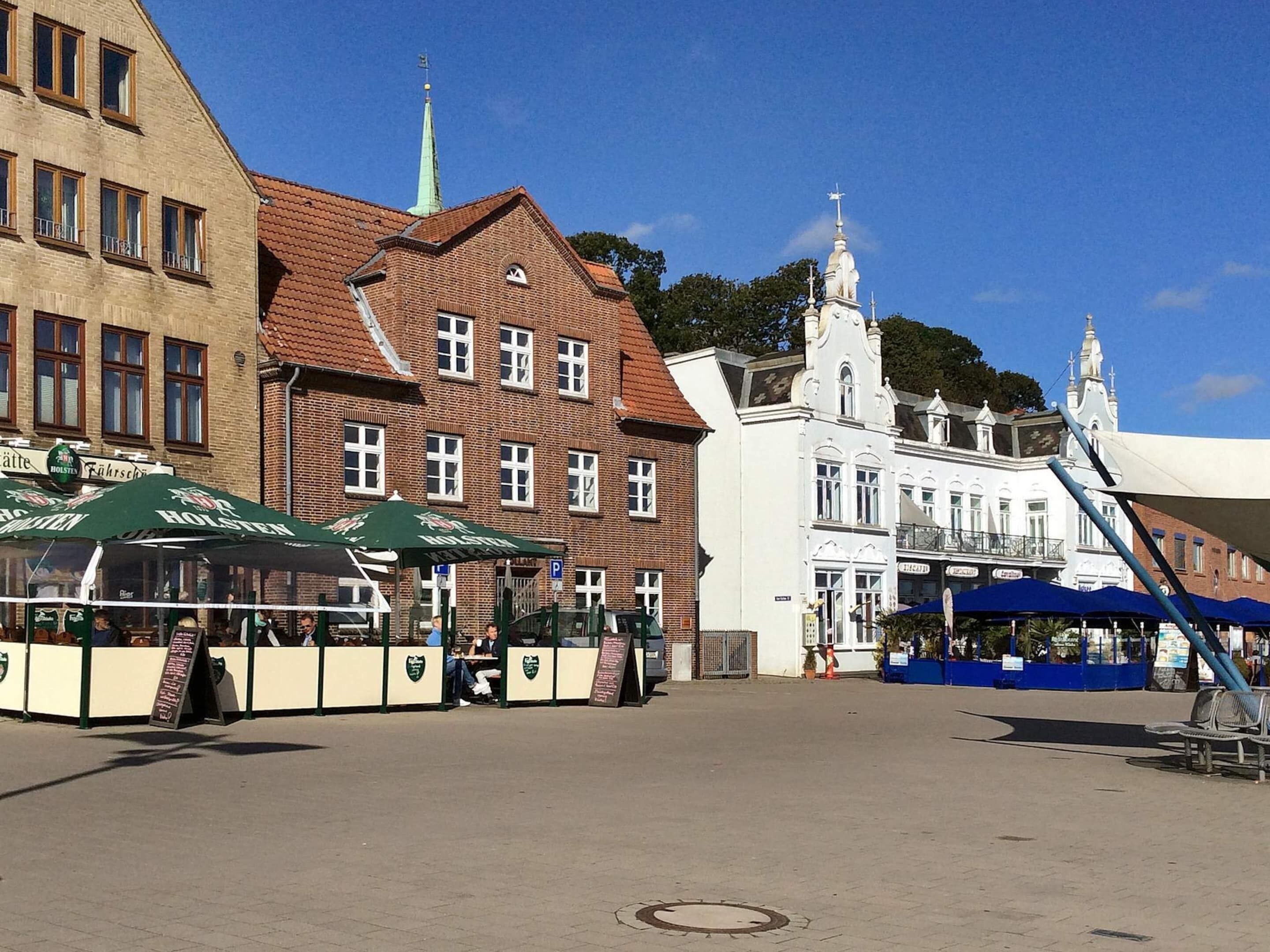 Ett offentligt torg med ett öltält, en kyrka och historiska byggnader.