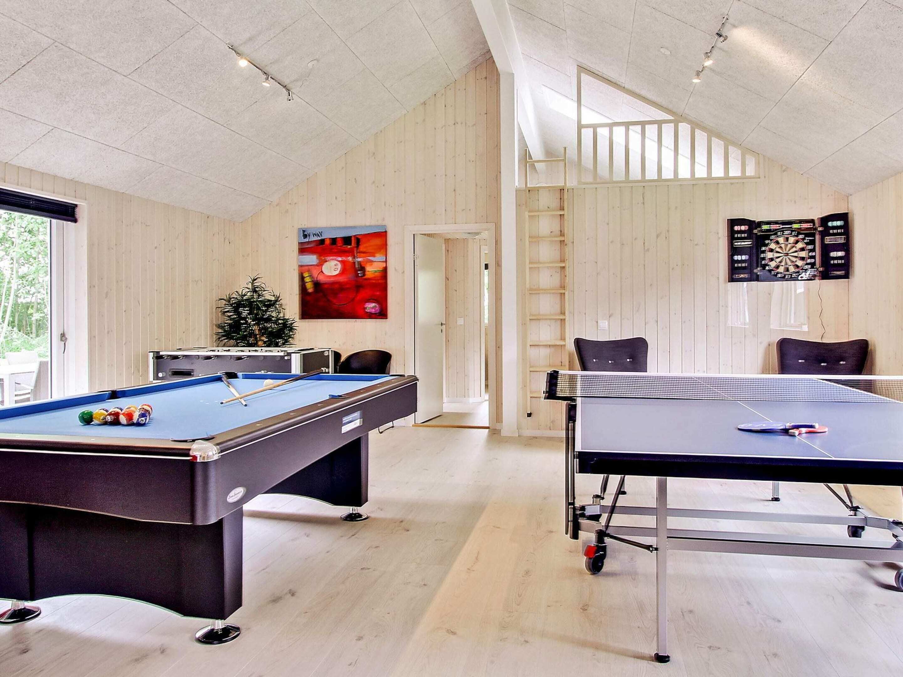 A room with a pool table, a ping pong table, and a dartboard.