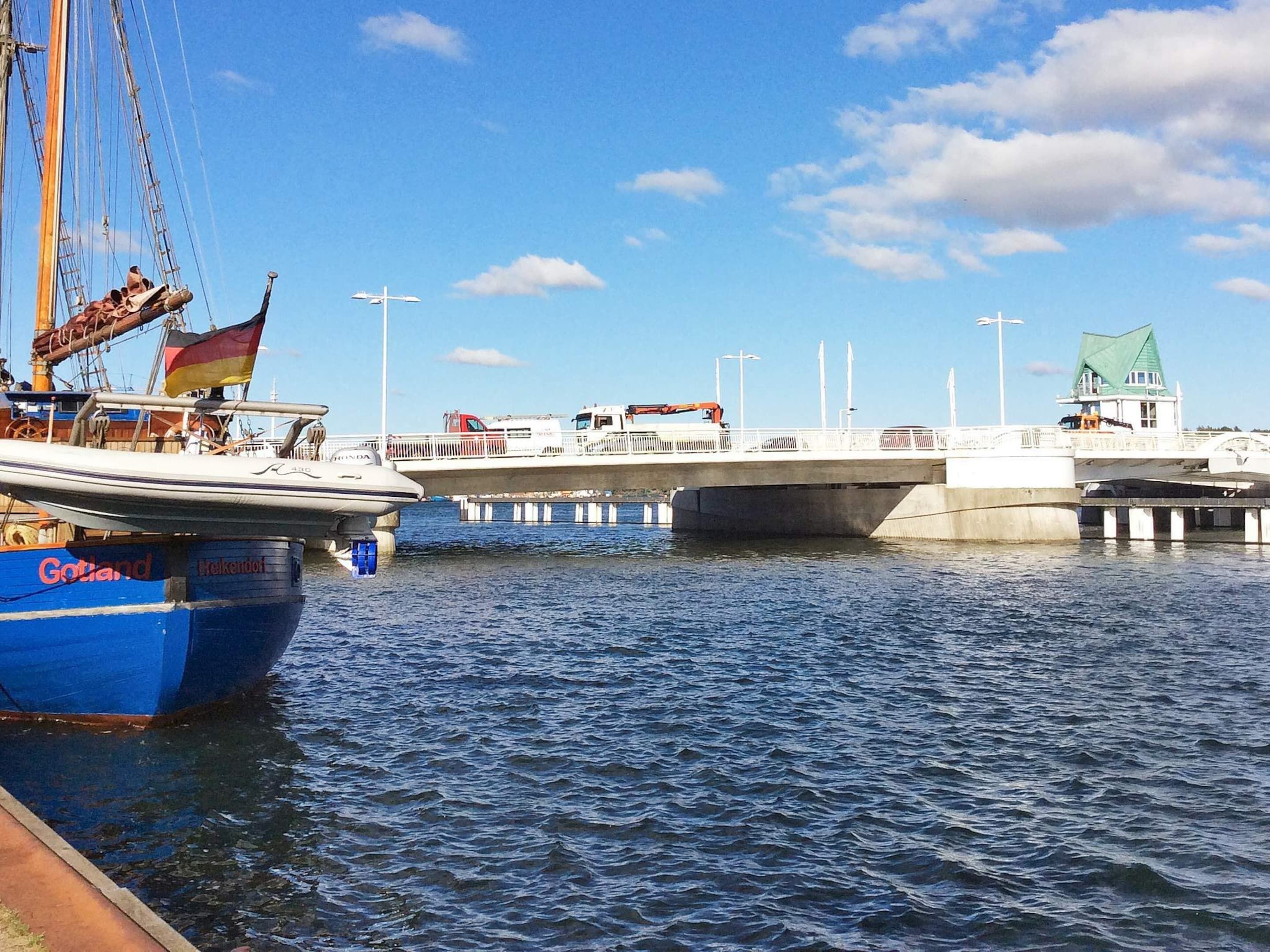 A harbor with boats, a bridge, and a green-roofed building.