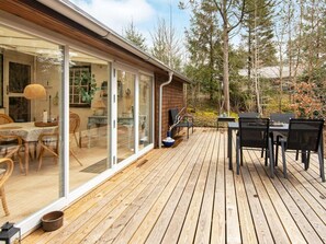 A wooden deck with outdoor furniture, a glass door leading to a dining area, and a view of trees. - 2 Person Holiday Home in Hemmet-by Traum (Hemmet)