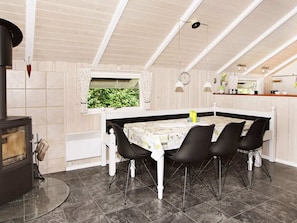 A dining area with a table, chairs, a stove, and a window with a view of greenery.