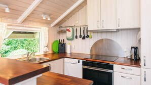A compact kitchen with white cabinets, a stainless steel sink, and a dishwasher. - 5 Star Holiday Home in Tarm (Tarm)