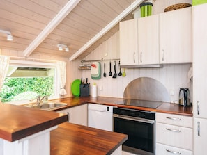 A compact kitchen with white cabinets, a stainless steel sink, and a dishwasher. - 5 Star Holiday Home in Tarm (Tarm)