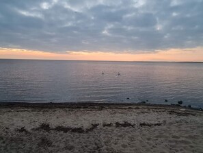 A beach with a sandy foreground and a calm sea.