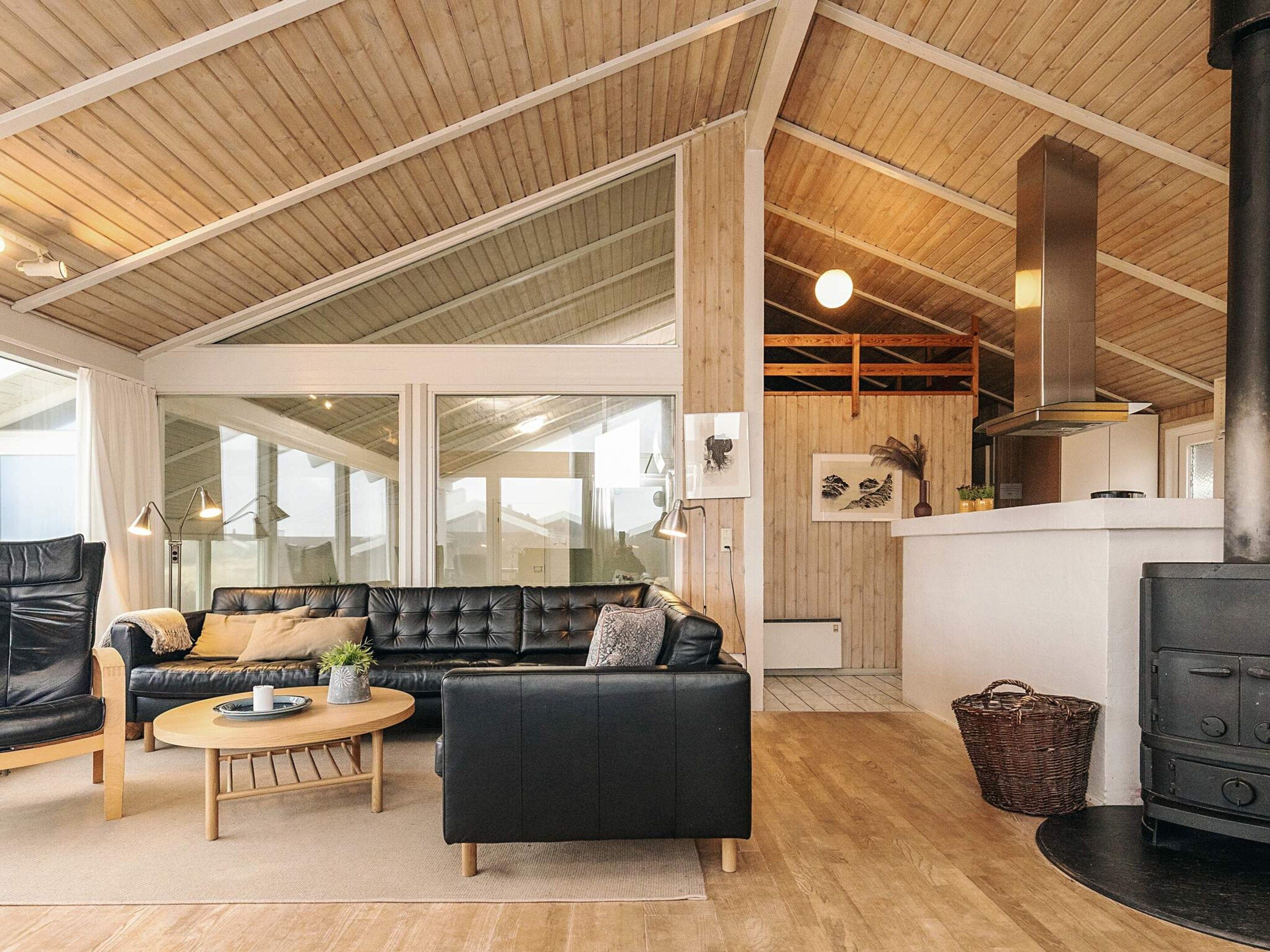 Ein modernes Wohnzimmer mit einem schwarzen Ledersofa, einem Holztisch und einem Kamin.