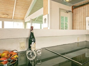 A kitchen area with a wine bottle, a fruit bowl, and a glass on a countertop. - 4 Star Holiday Home in Lokken (Lokken)