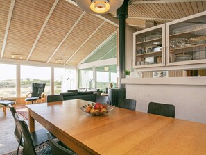 Un comedor amplio con una mesa y sillas de madera, un cuenco de fruta y vistas al exterior.