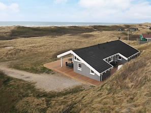 A modern house with a flat roof, a wooden deck, and a view of the beach. - 4 Star Holiday Home in Lokken (Lokken)
