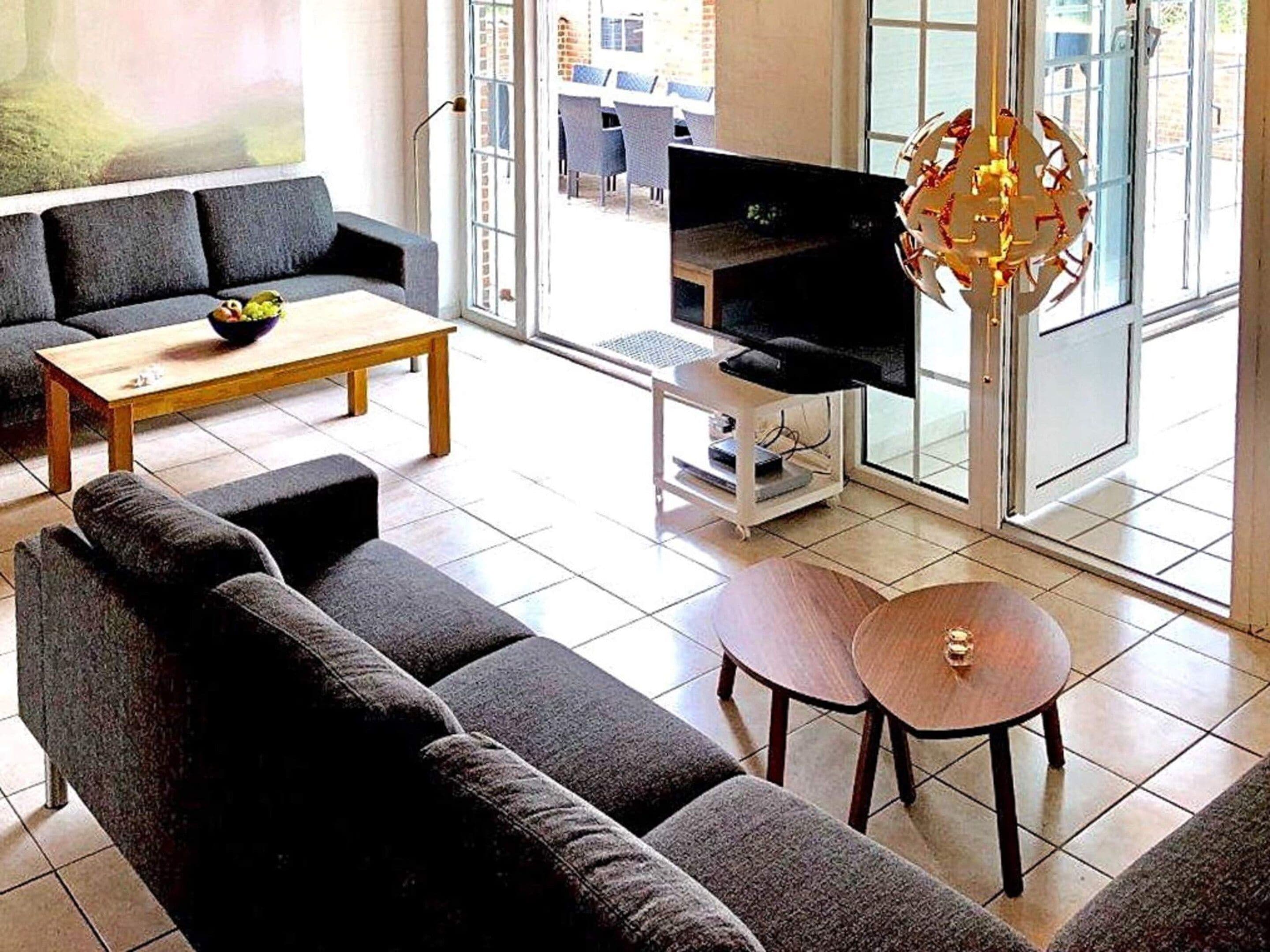 A modern living room with a sofa set, a coffee table, a TV on a stand, and a decorative light fixture.