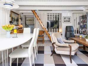 A modern living room with a dining area, a fireplace, and a kitchen in the background. - 6 Person Holiday Home in Glesborg (Glesborg)