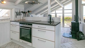 A modern kitchen with white cabinetry, a built-in oven, and a large window overlooking a scenic view. - 4 Star Holiday Home in Hjorring (Hjørring)