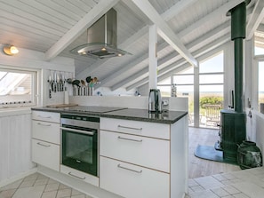 Une cuisine moderne avec des meubles blancs, un four encastré et une grande fenêtre donnant sur un paysage magnifique.