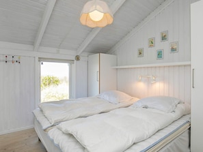 A bedroom with two beds, a hanging light fixture, a window with blinds, and wall-mounted artwork.