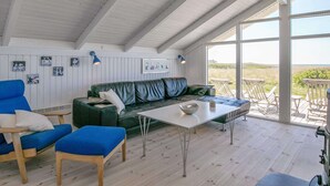 A modern interior with a high ceiling, wooden flooring, a green sofa, blue chairs, and a dining table. - 4 Star Holiday Home in Hjorring (Hjørring)