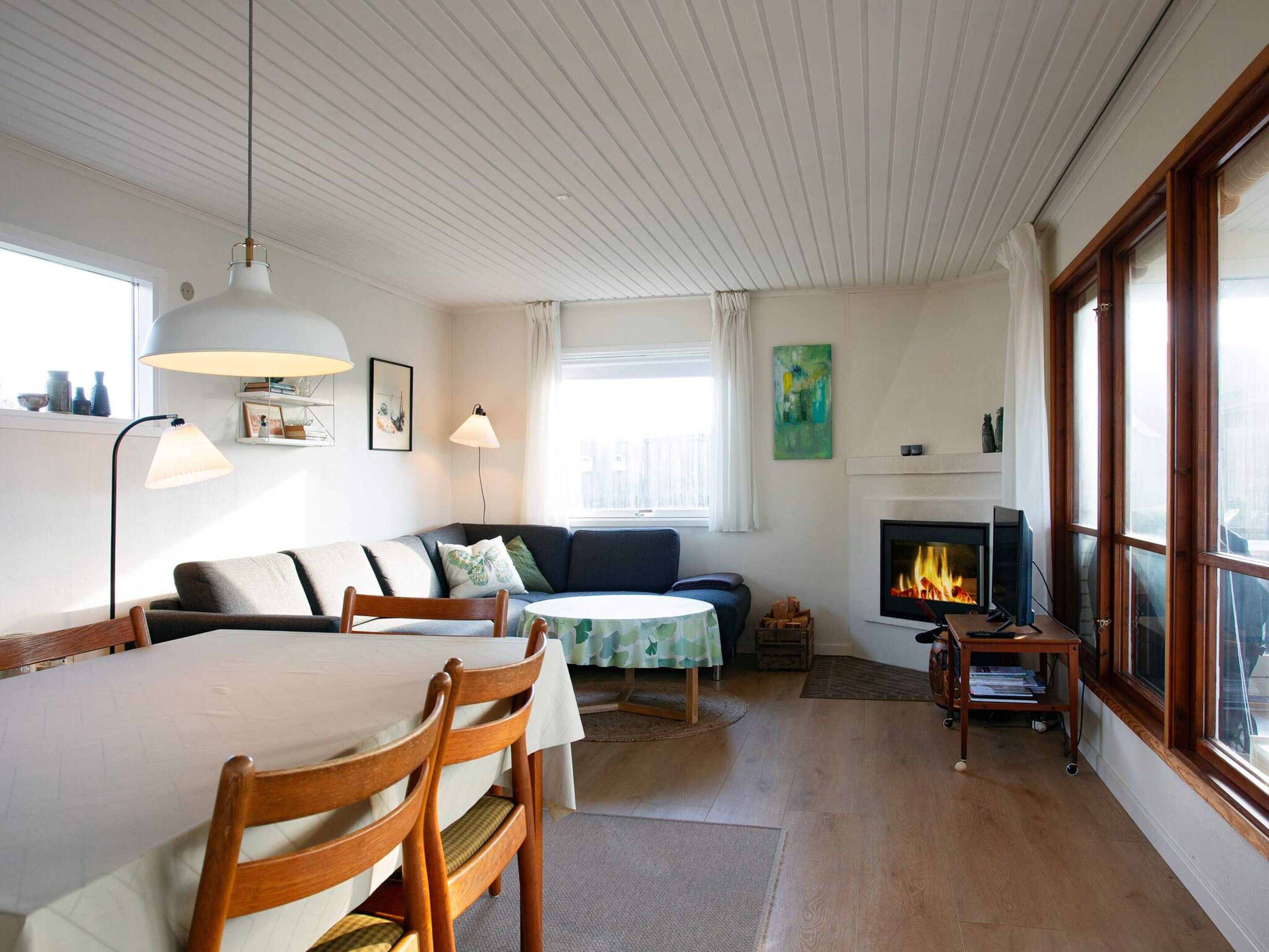 A cozy living room with a fireplace, a dining table, and a sofa.