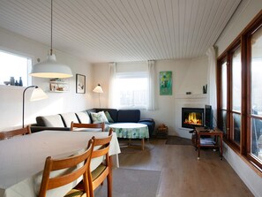 A cozy living room with a fireplace, a dining table, and a sofa.