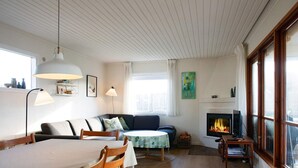 Ett mysigt vardagsrum med en öppen spis, en matplats och en soffa.