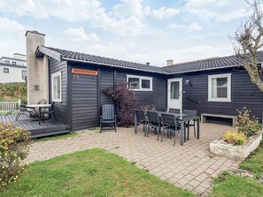 A two-story house with a dark exterior, a chimney, and a sign reading 'Vestkysten 23'. - 6 Person Holiday Home in Lokken (Lokken)