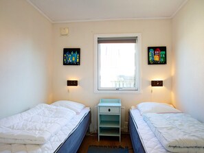 A bedroom with two beds, a window with a view, and two wall-mounted light switches.
