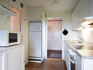A compact kitchen with white cabinetry, a microwave, a refrigerator, a stove, and a sink.