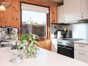 A kitchen with wooden cabinets, a stainless steel stove, and a window with a view of greenery.