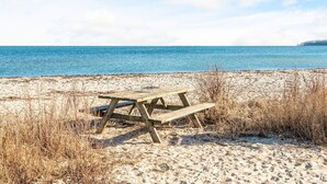 A wooden picnic table on a sandy beach with the ocean in the background. - 4 Star Holiday Home in Juelsminde (Juelsminde)