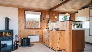 A cozy kitchen with wooden walls, a built-in stove, and a window overlooking a garden. - 4 Star Holiday Home in Juelsminde (Juelsminde)