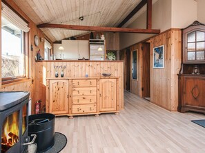 A wooden interior with a fireplace, wooden cabinets, and a kitchen area.