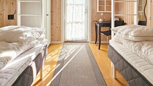 Ein kleines Zimmer mit zwei Etagenbetten, einem kleinen Schreibtisch und einer Tür zu einem Außenbereich.