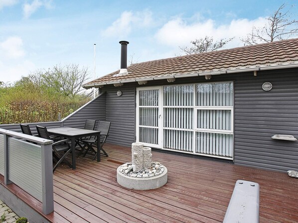 A deck with a table and chairs, a stone planter, and a chimney.