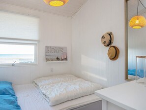 A bedroom with a bed, a window with a view, a 'HOME' sign, and two hats on the wall. - Peaceful Holiday Home in Fjerritslev near Beaches (Sjølund)
