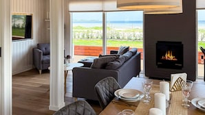 A modern living room with a fireplace, a sofa, and a dining area set for a meal. - Peaceful Holiday Home in Fjerritslev near Beaches (Sjølund)