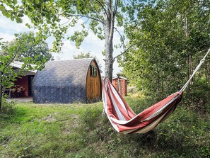 A hammock tied to a tree, a hexagonal building, and a smaller wooden structure in a grassy area. - Pretty Holiday Home in Ålbæk near Sea (Aalbaek)