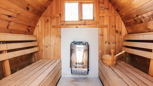 A wooden sauna with benches, a sauna heater, and a window. - Pretty Holiday Home in Ålbæk near Sea (Aalbaek)
